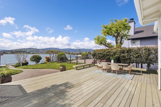 wooden deck featuring outdoor dining space, fence, and a water and mountain view