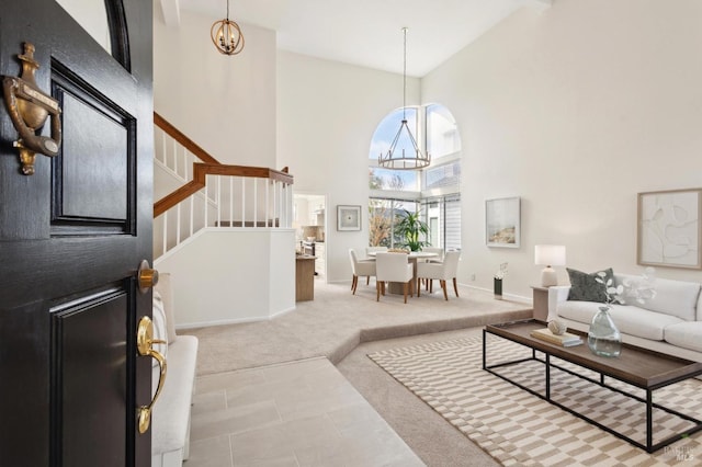 carpeted living area with a notable chandelier, baseboards, a high ceiling, and stairway