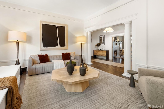 living room with decorative columns, crown molding, and hardwood / wood-style floors