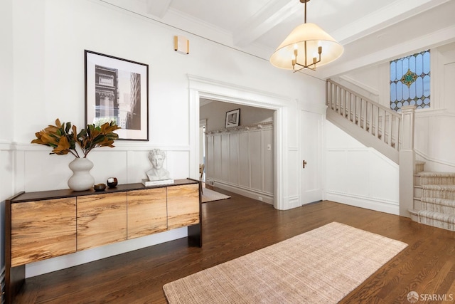 foyer entrance with dark wood-type flooring, ornamental molding, and beam ceiling