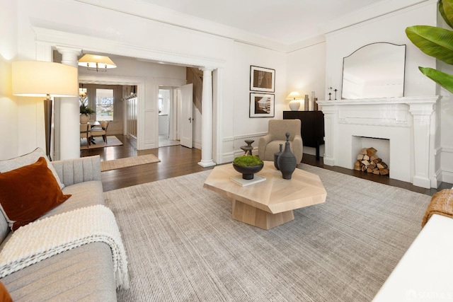 living room featuring crown molding, dark hardwood / wood-style flooring, and decorative columns