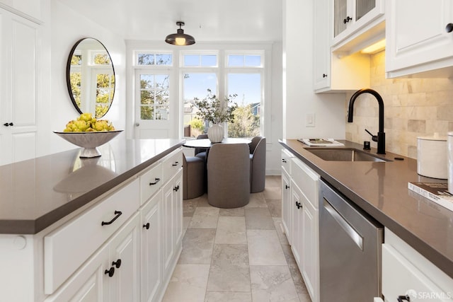 kitchen with sink, stainless steel dishwasher, white cabinets, and backsplash