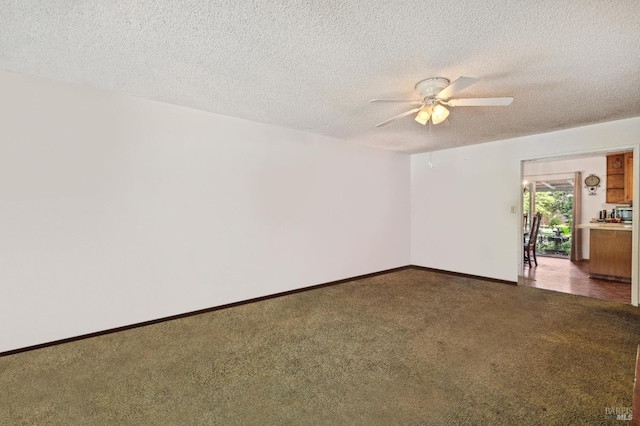 spare room featuring a textured ceiling, dark carpet, and ceiling fan