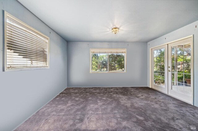 spare room with french doors and dark carpet