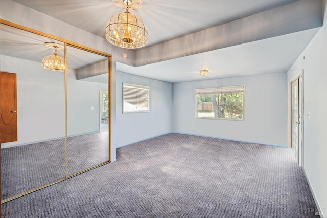 unfurnished bedroom with carpet flooring, a notable chandelier, and a closet