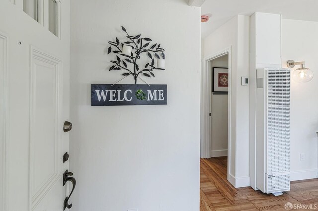 hall featuring baseboards, a heating unit, and light wood-type flooring