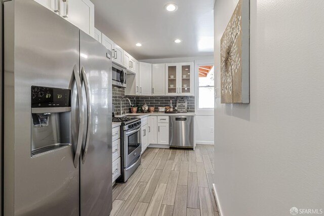 kitchen featuring backsplash, wood finish floors, recessed lighting, stainless steel appliances, and white cabinetry