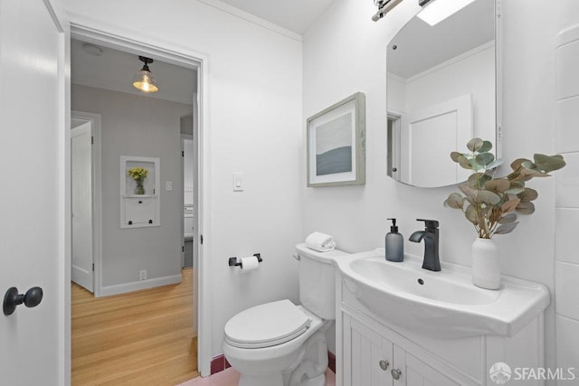 bathroom with hardwood / wood-style flooring, crown molding, vanity, and toilet