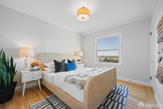 bedroom featuring crown molding and light hardwood / wood-style flooring