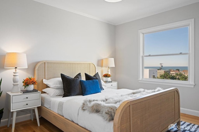 bedroom with hardwood / wood-style flooring, ornamental molding, and a water view