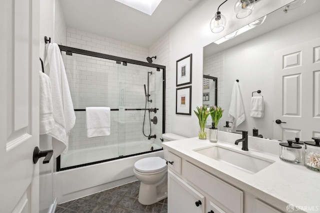 full bathroom with combined bath / shower with glass door, vanity, and toilet