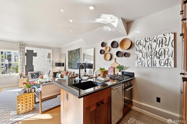 kitchen featuring stainless steel appliances, a sink, baseboards, open floor plan, and dark countertops