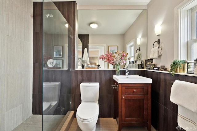 bathroom with a shower, tile walls, toilet, and vanity