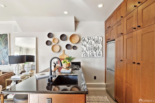 kitchen with stainless steel fridge, brown cabinets, tile patterned flooring, a sink, and recessed lighting