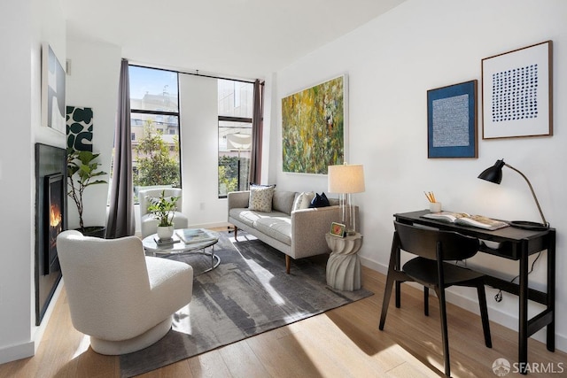 sitting room with light wood-type flooring and a wall of windows