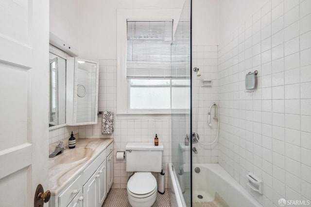 full bathroom with vanity, tiled shower / bath combo, tile patterned flooring, tile walls, and toilet