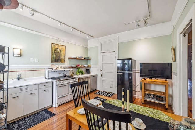 kitchen with rail lighting, light hardwood / wood-style floors, white cabinetry, gas range gas stove, and black refrigerator