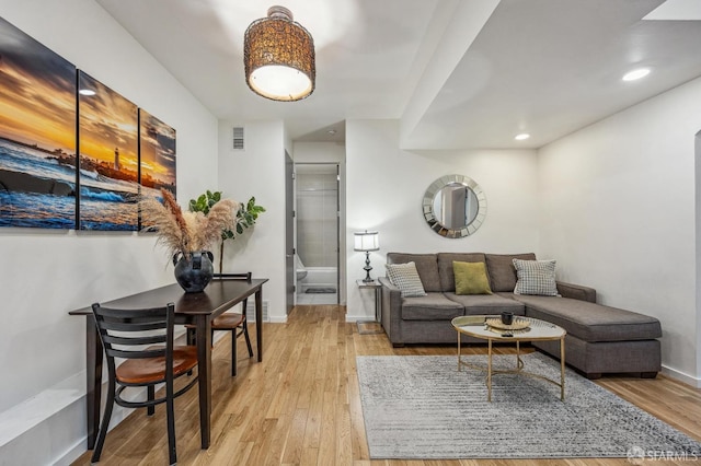 living room featuring light wood-type flooring, baseboards, visible vents, and recessed lighting