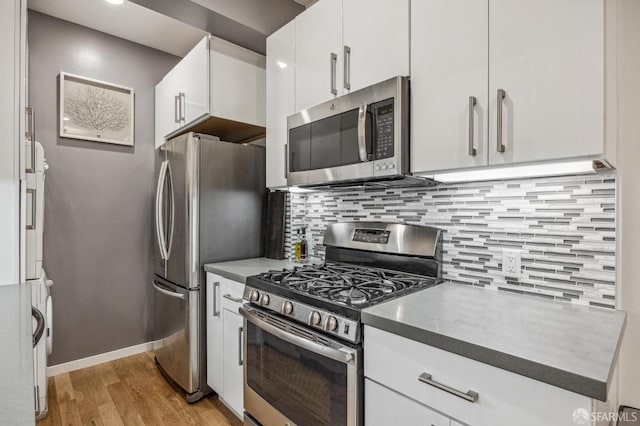 kitchen with light wood-type flooring, white cabinetry, stainless steel appliances, and backsplash