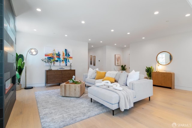 living room featuring recessed lighting, baseboards, light wood-style flooring, and a tile fireplace