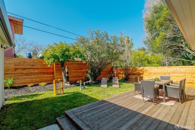 wooden deck with a lawn, outdoor dining area, and a fenced backyard