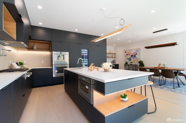 kitchen featuring a breakfast bar, modern cabinets, appliances with stainless steel finishes, exhaust hood, and light countertops