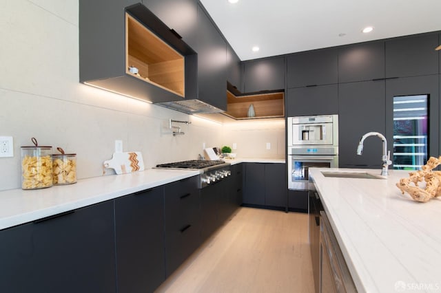 kitchen featuring light wood finished floors, a sink, light countertops, stainless steel appliances, and modern cabinets