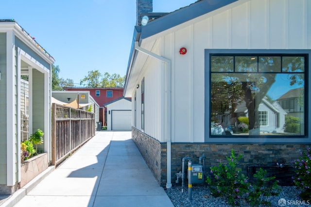 view of property exterior with stone siding, a detached garage, board and batten siding, and an outdoor structure