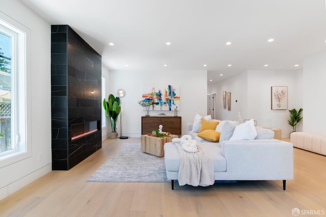 living room with recessed lighting, light wood-style floors, and a tile fireplace