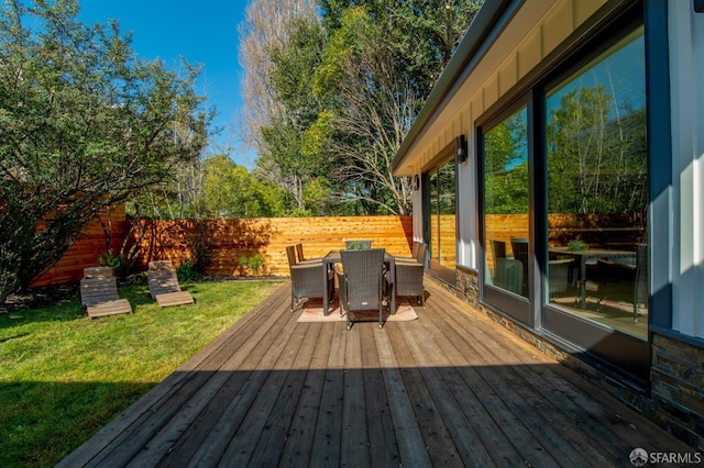 deck with outdoor dining area, a yard, and fence