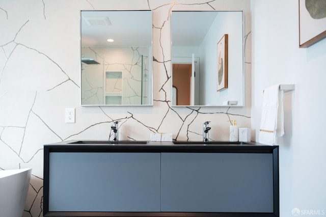 bathroom featuring double vanity, tasteful backsplash, a marble finish shower, and a sink