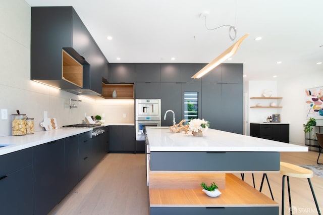 kitchen with double oven, modern cabinets, stainless steel gas stovetop, and light countertops