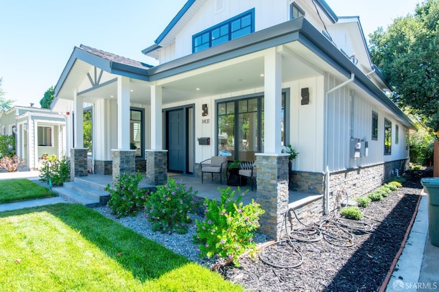 view of front of house with covered porch, board and batten siding, and a front yard