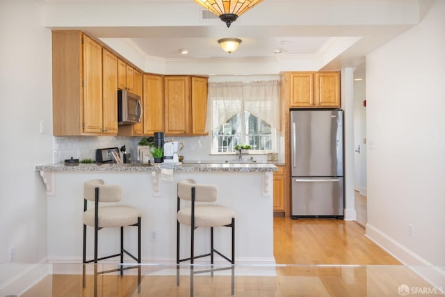 4471 Mission St Unit 2, San Francisco, CA 94112 - kitchen featuring appliances with stainless steel finishes, a breakfast bar, a peninsula, backsplash, and light wood-type flooring
