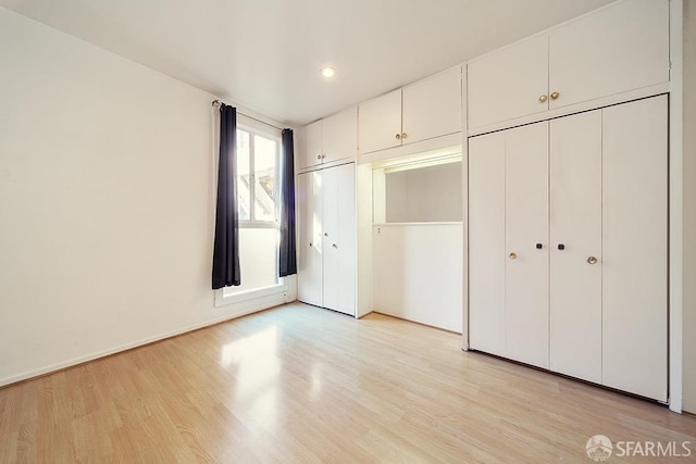 unfurnished bedroom featuring light wood-style floors, two closets, and recessed lighting