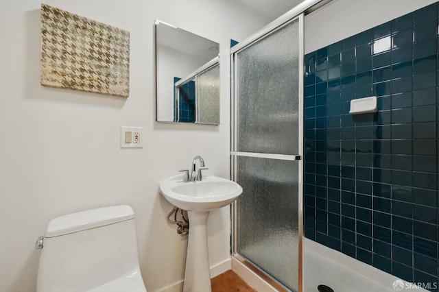 bathroom with sink, a tile shower, and toilet