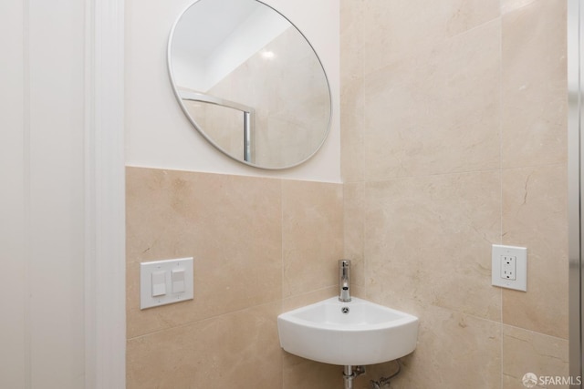 bathroom with a sink and tile walls