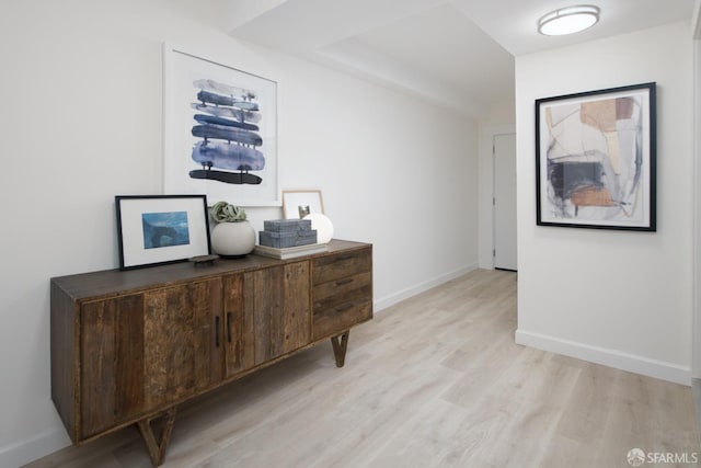 corridor featuring baseboards and light wood finished floors