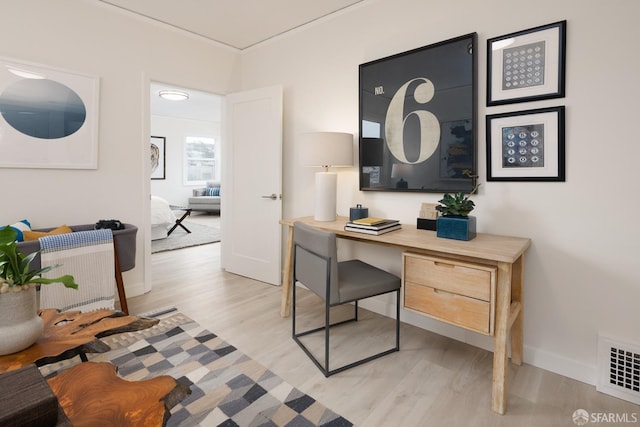 office space with baseboards, visible vents, and light wood-style floors