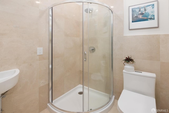 bathroom featuring toilet, a stall shower, and tile walls