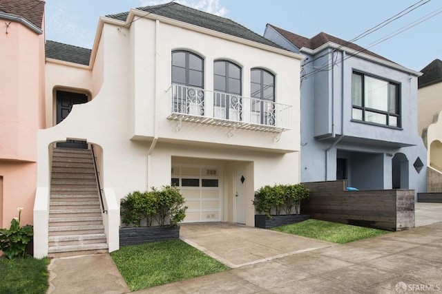 view of front of home featuring an attached garage, a balcony, driveway, and stucco siding