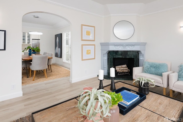 living area featuring arched walkways, a fireplace, wood finished floors, and baseboards