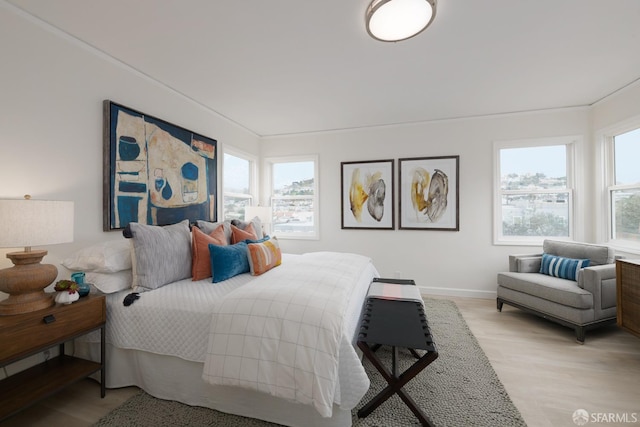 bedroom featuring multiple windows, light wood-style flooring, and baseboards