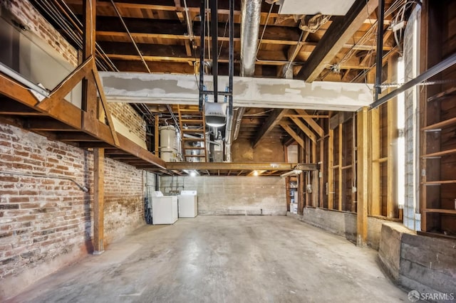 basement with washer and clothes dryer and brick wall