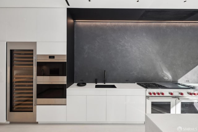 kitchen with wine cooler, stainless steel appliances, sink, and white cabinets