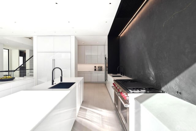 kitchen with double oven range, sink, and white cabinets