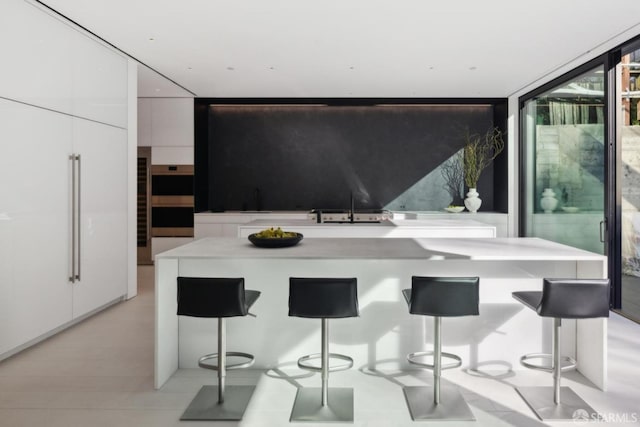 kitchen featuring sink, white cabinets, a kitchen bar, and a wall of windows