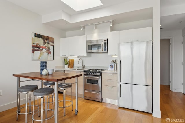 566 S Van Ness Ave Unit 31, San Francisco, CA 94110 - kitchen featuring appliances with stainless steel finishes, a skylight, light countertops, track lighting, and white cabinets