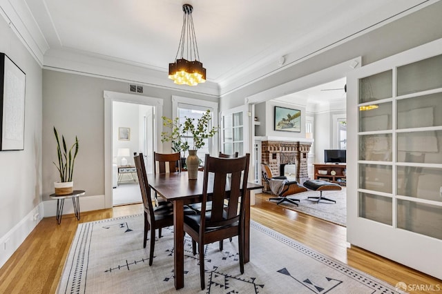 207 Eureka St, San Francisco, CA 94114 - dining space with wood finished floors, a fireplace, crown molding, a chandelier, and baseboards