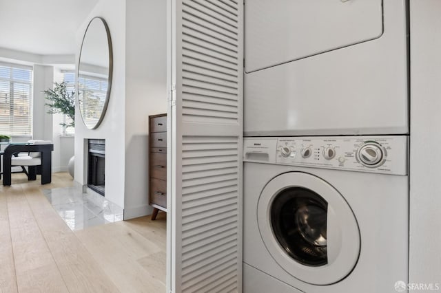 washroom with stacked washer / drying machine, baseboards, and laundry area